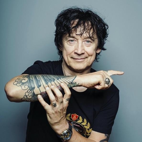 Jan Borysewicz z bliska, grający na gitarze elektrycznej na scenie, z rozmytym tłem świateł koncertowych.