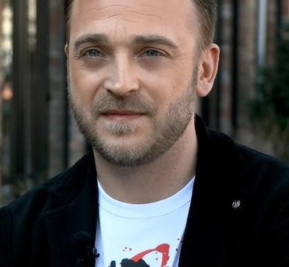 Mateusz Gessler w swobodnej, zamyślonej pozie, symbolizującej prywatność jego życia.