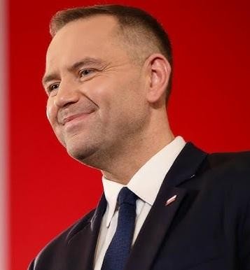 Karol Nawrocki w otoczeniu eksponatów historycznych, symbolizujących jego zaangażowanie w edukację historyczną i upamiętnianie przeszłości.