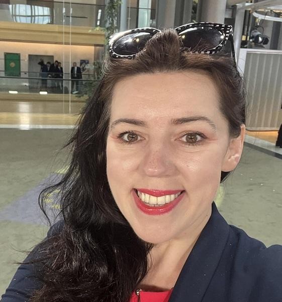 Dominika Ćosić jako aktywna dziennikarka, w tle elementy związane z polityką międzynarodową lub Bałkanami, podkreślające jej profesjonalizm.