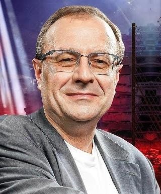 Antoni Dudek w zamyślonej pozie, na tle biblioteki, symbolizującej jego wiedzę historyczną.