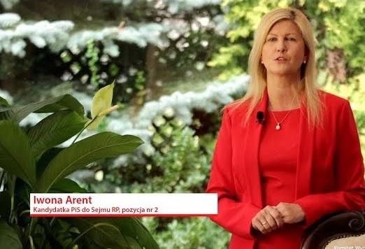 Iwona Arent w dynamicznej pozie w parlamencie, przemawiająca lub uczestnicząca w debacie.
