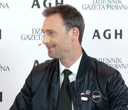 Sławosz Uznański w stroju treningowym astronauty, skupiony i zdeterminowany, w tle nowoczesne technologie symulacyjne, symbolizujące przygotowania do lotu w kosmos.