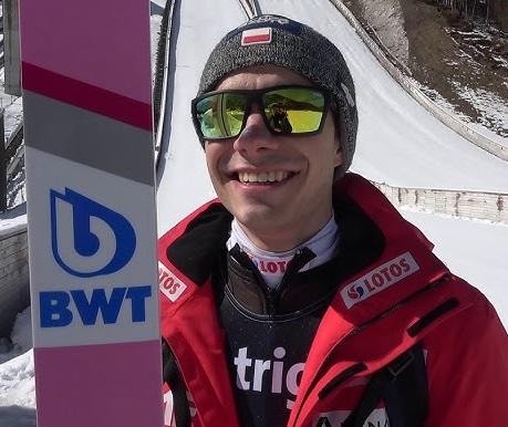 Jakub Wolny wybija się z progu skoczni, zdeterminowany wyraz twarzy i skupienie na technice.